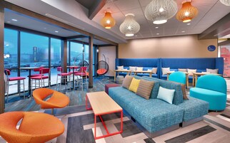 Un área de lounge moderna con asientos, mesas y vistas amplias a través de grandes ventanales.