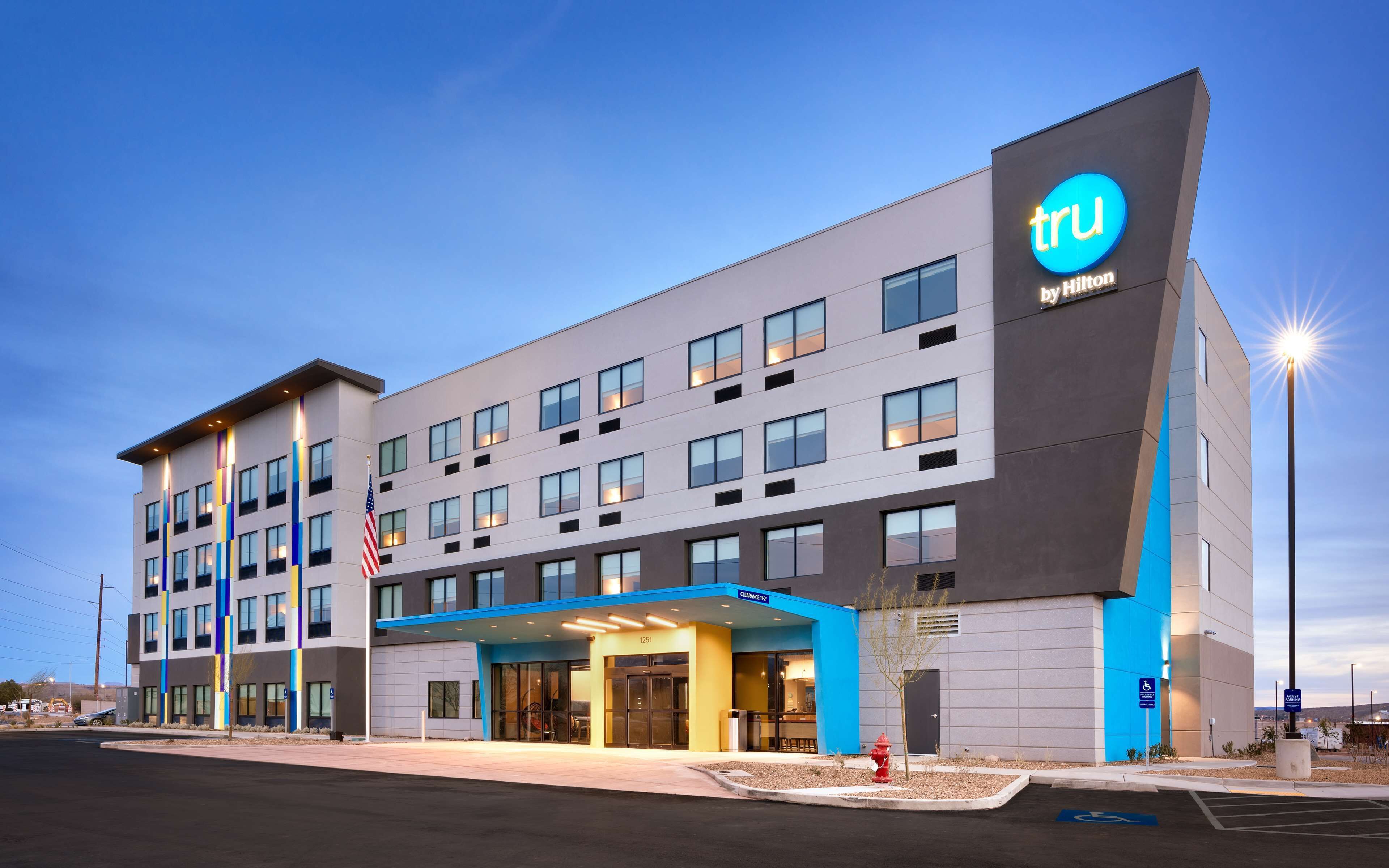 Een modern hotel met een opvallend 'tru by Hilton'-bord, meerdere verdiepingen en een goed verlichte entree.