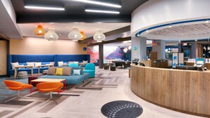 A modern hotel lobby with seating areas, a reception desk, and a mural on the wall. - Tru By Hilton St George, UT (St. George)