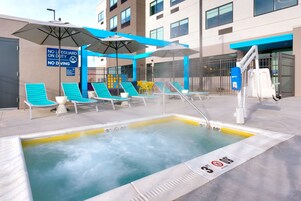 Zona de piscina en la azotea con sillones de descanso y sombrillas, un letrero de prohibición de buceo y una silla para salvavidas.