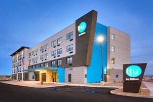 Un hotel moderno con un llamativo letrero 'tru by Hilton', varios pisos y un estacionamiento.