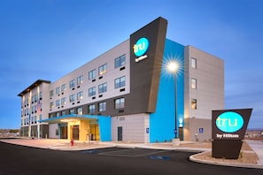 A modern hotel with a prominent 'tru by Hilton' sign, multiple floors, and a parking lot.