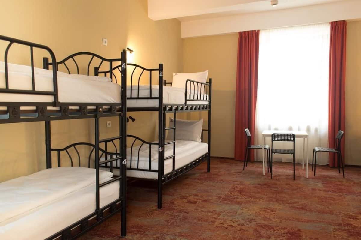 A room with bunk beds, a small table, and two chairs.