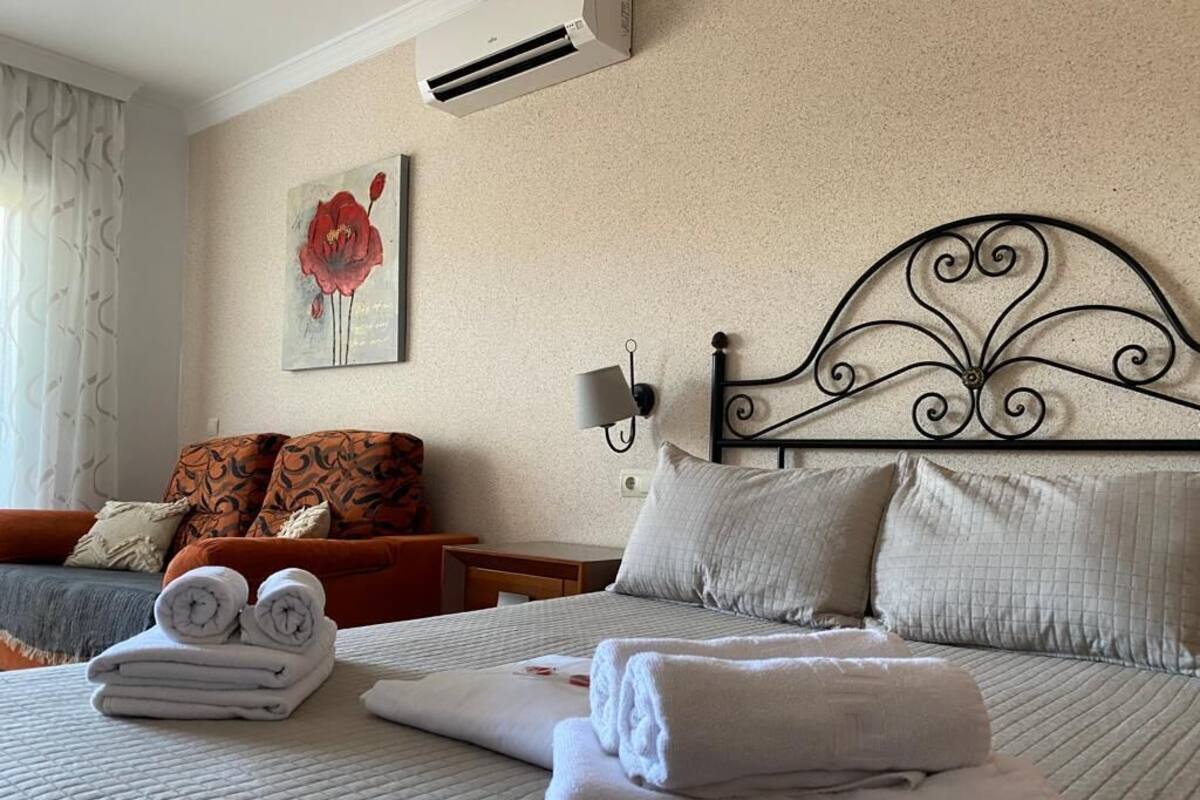 Une chambre d’hôtel avec un lit, des oreillers, une table de chevet, une lampe et un tableau au mur.