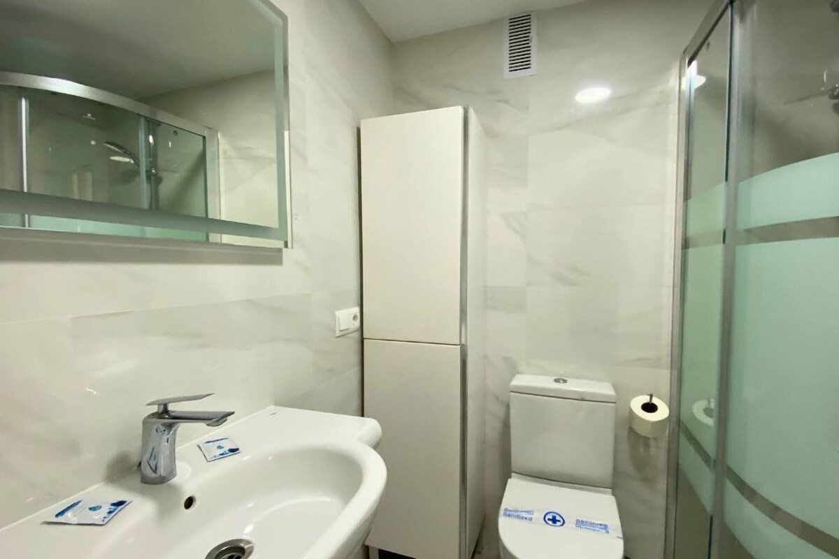 Une salle de bain moderne avec un lavabo blanc, des toilettes et une douche à parois de verre.