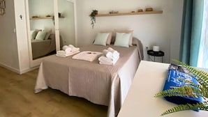 A bedroom with a bed, a wardrobe, a bedside table, a plant, and a window with curtains.
