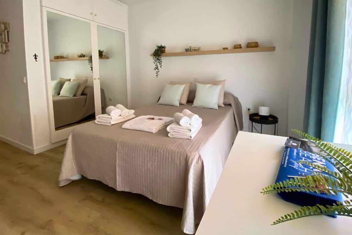 Une chambre à coucher avec un lit, une armoire, une table de chevet et une fenêtre avec des rideaux.