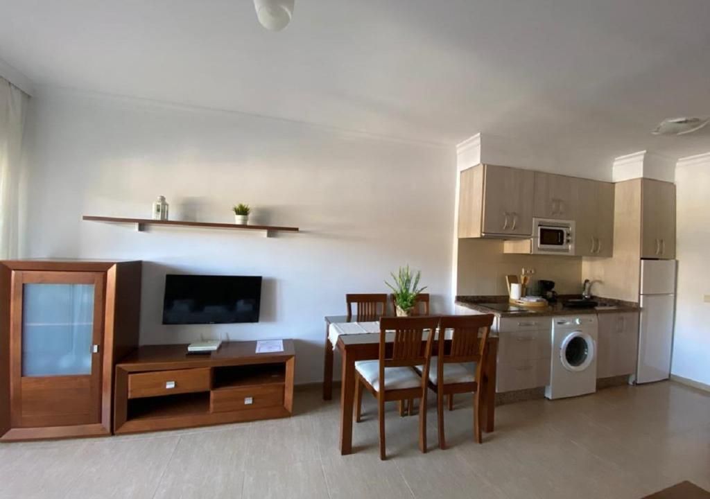 A compact living space with a dining area, kitchenette, and a flat-screen TV.