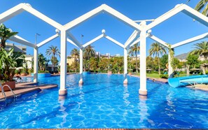 Una piscina con pilares blancos y un cielo azul despejado.