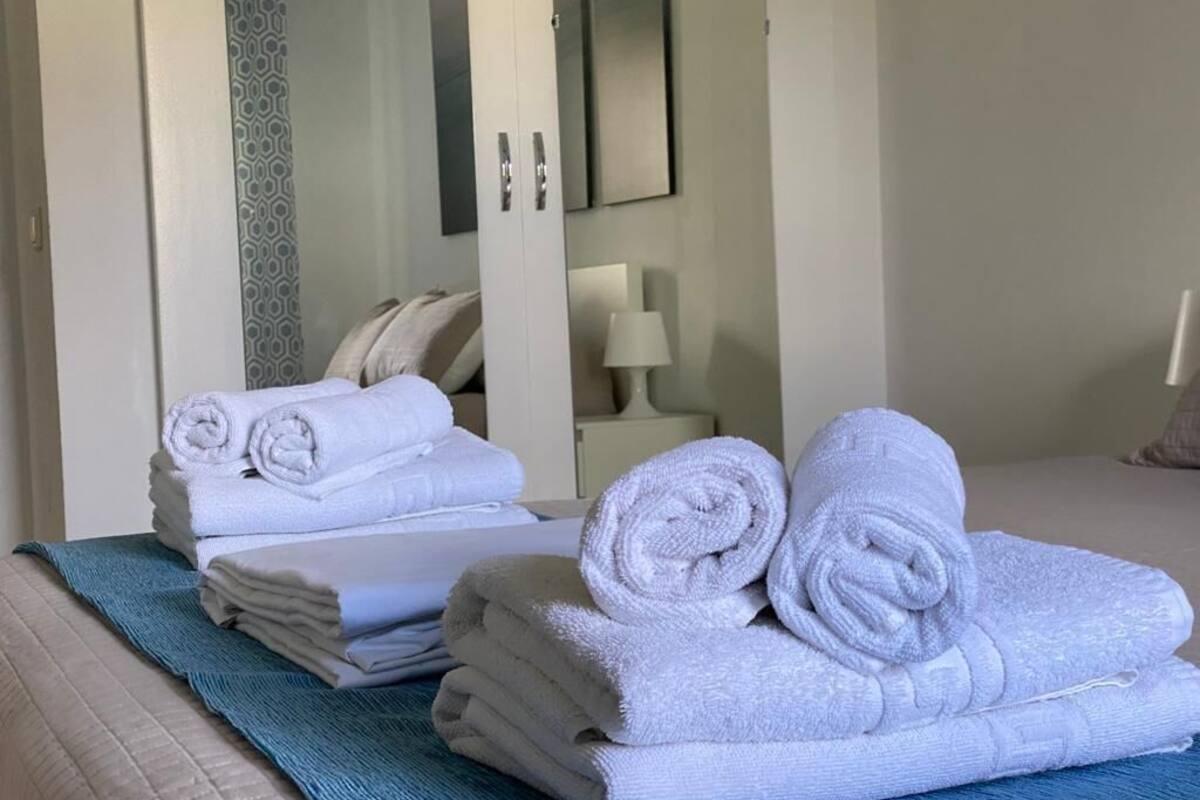 Une pile de serviettes soigneusement rangée sur un lit dans une chambre d’hôtel.