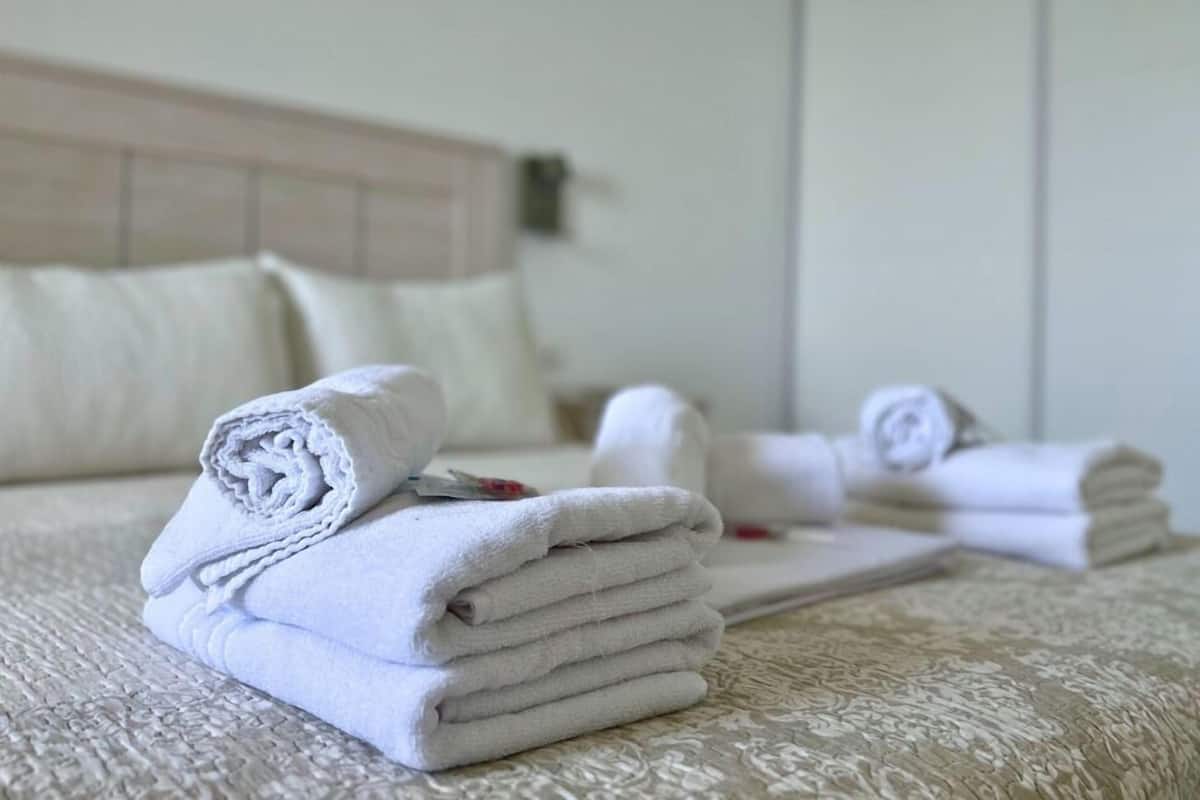 Un lit bien fait, avec des serviettes blanches pliées et une tête de lit.