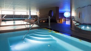 Una piscina interior moderna con agua cristalina, varias pistas y una isla central.