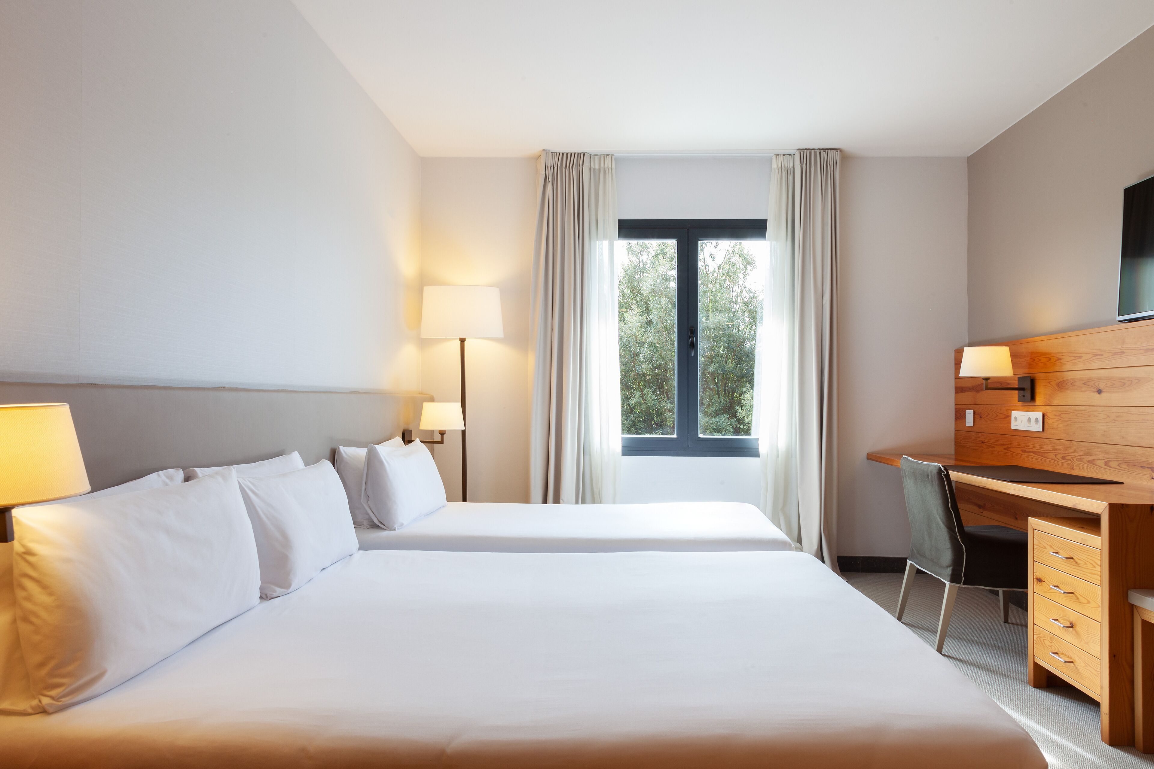 Een hotelkamer met twee bedden, een bureau, een stoel en een televisie.