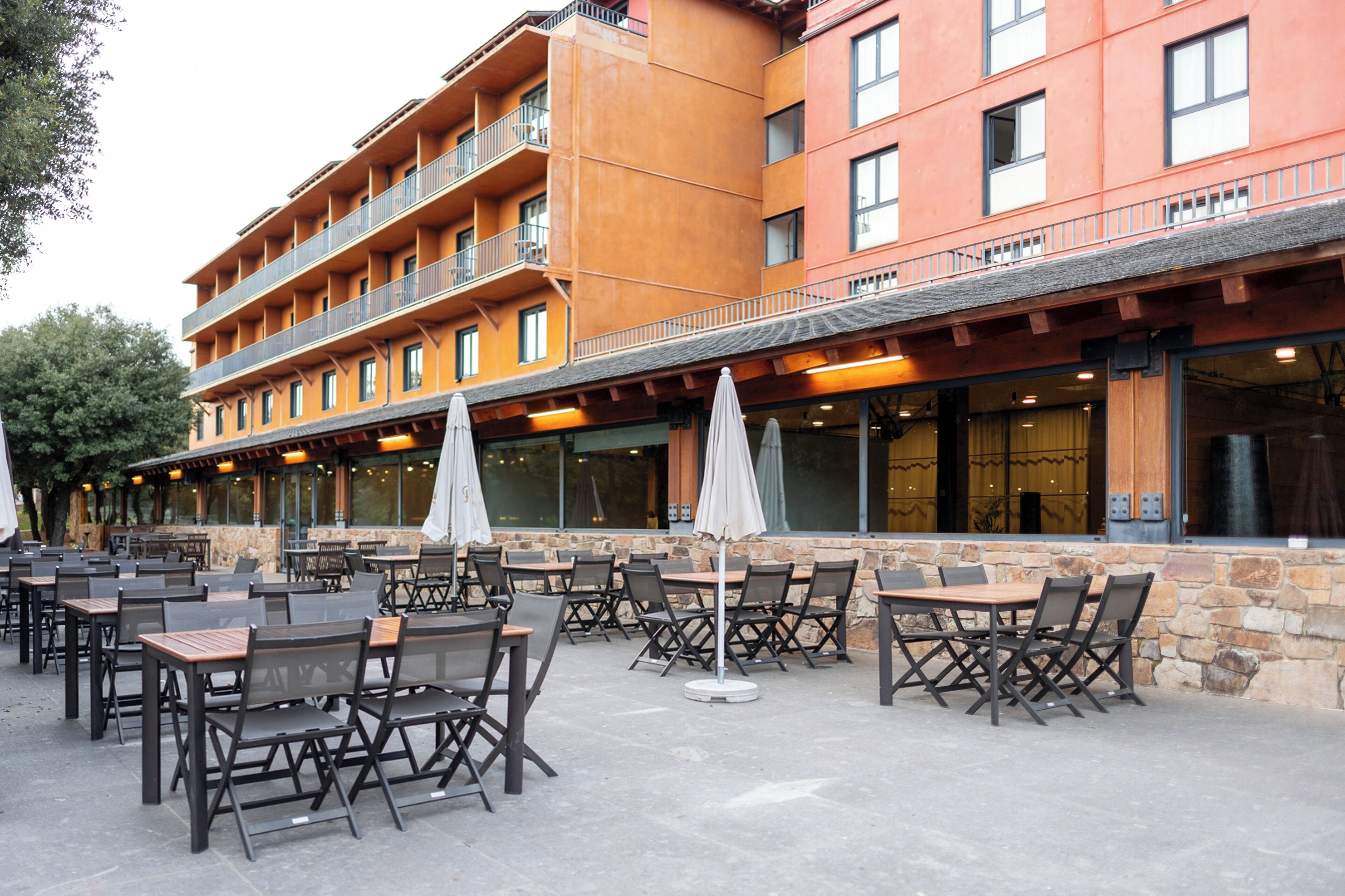 A multi-story hotel with outdoor seating and a stone facade.
