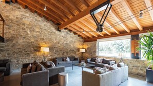 Un amplio espacio habitable con pared de piedra, vigas de madera en el techo y mobiliario moderno.