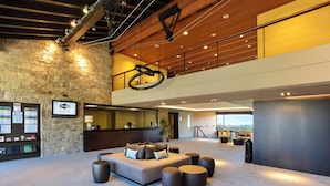 A spacious lobby with a large sofa, multiple seating options, a reception desk, and a stone wall with informational displays.