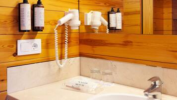 A bathroom with a wooden panel wall, a white sink, a mirror, and toiletries on the wall.