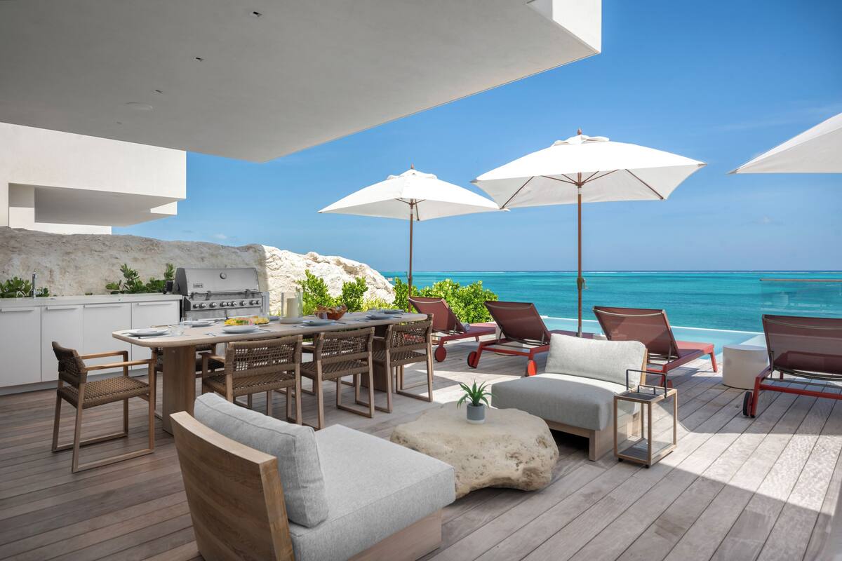 An outdoor patio with a dining area, lounge chairs, and a grill.