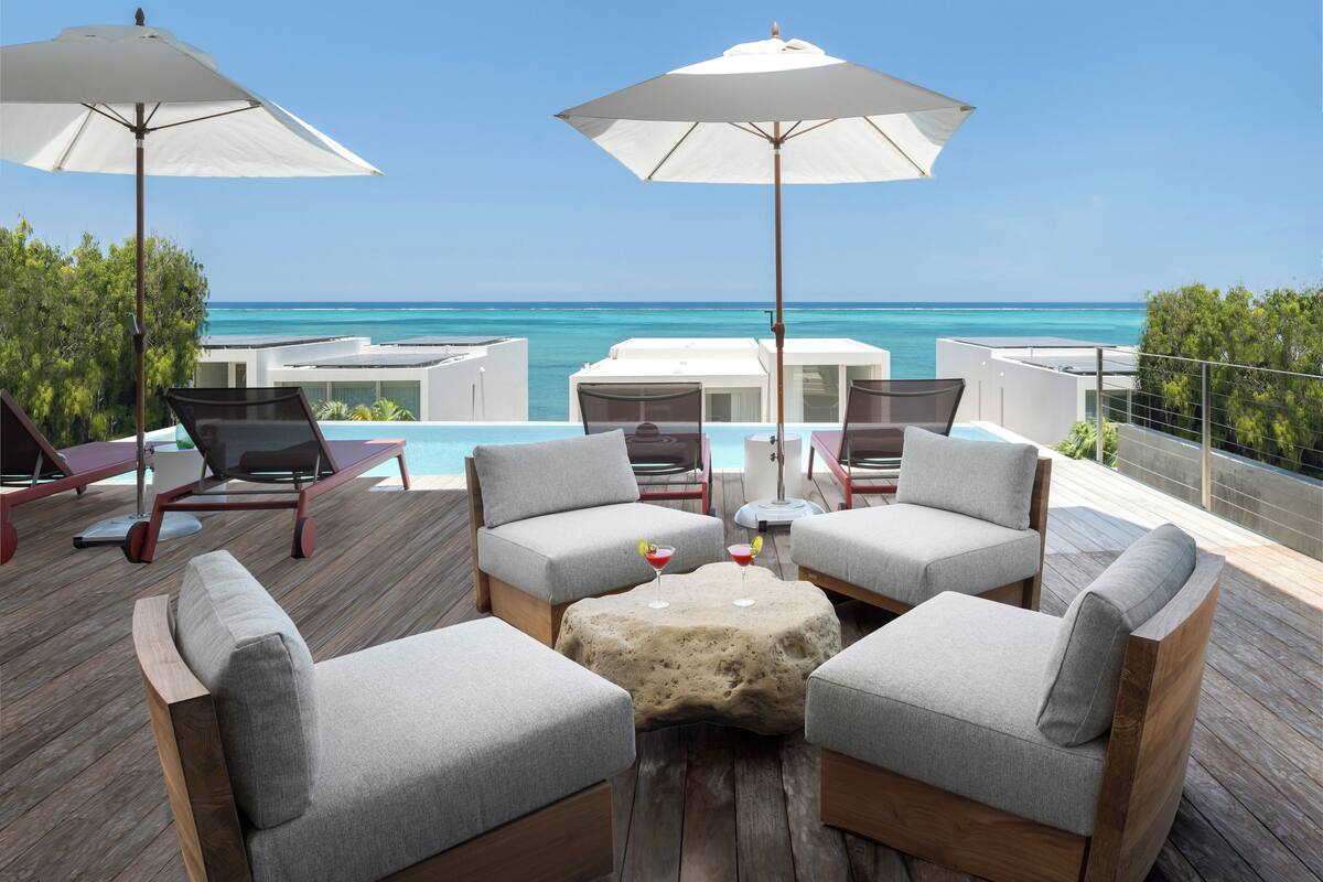 A deck with outdoor seating, umbrellas, and a view of the ocean.