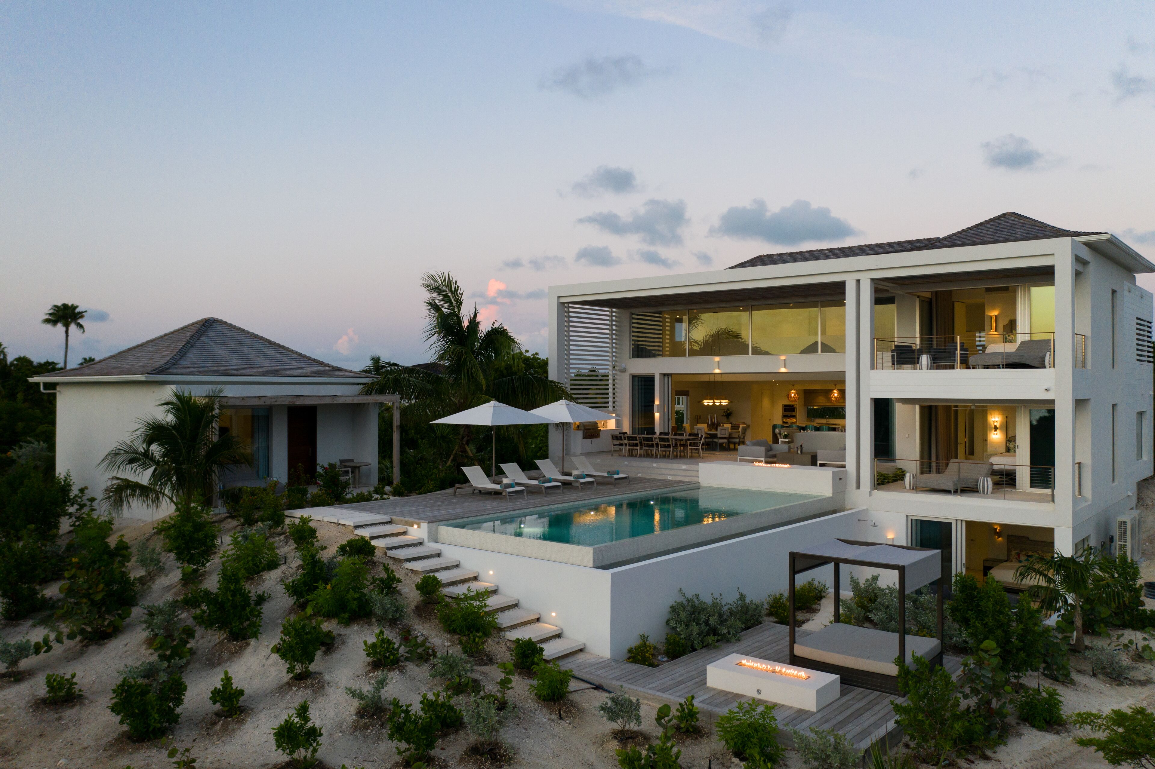 Uma casa moderna de dois andares com piscina, área de estar externa e vista para o oceano.