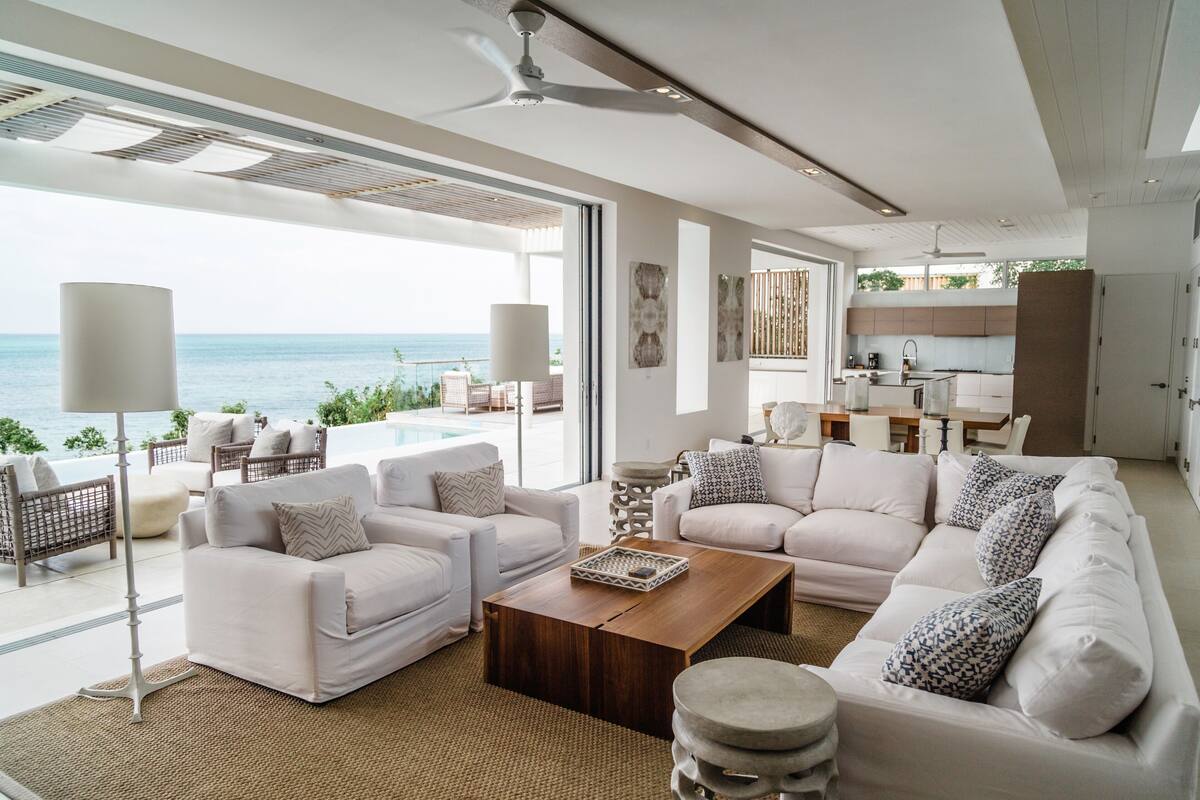 A spacious living area with a large sofa set, a coffee table, and a view of the ocean.