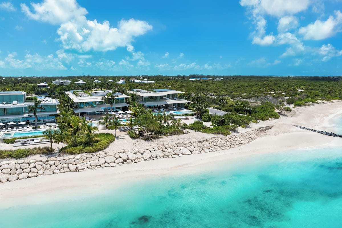An aerial view of a resort with multiple buildings, a swimming pool, and a beach.