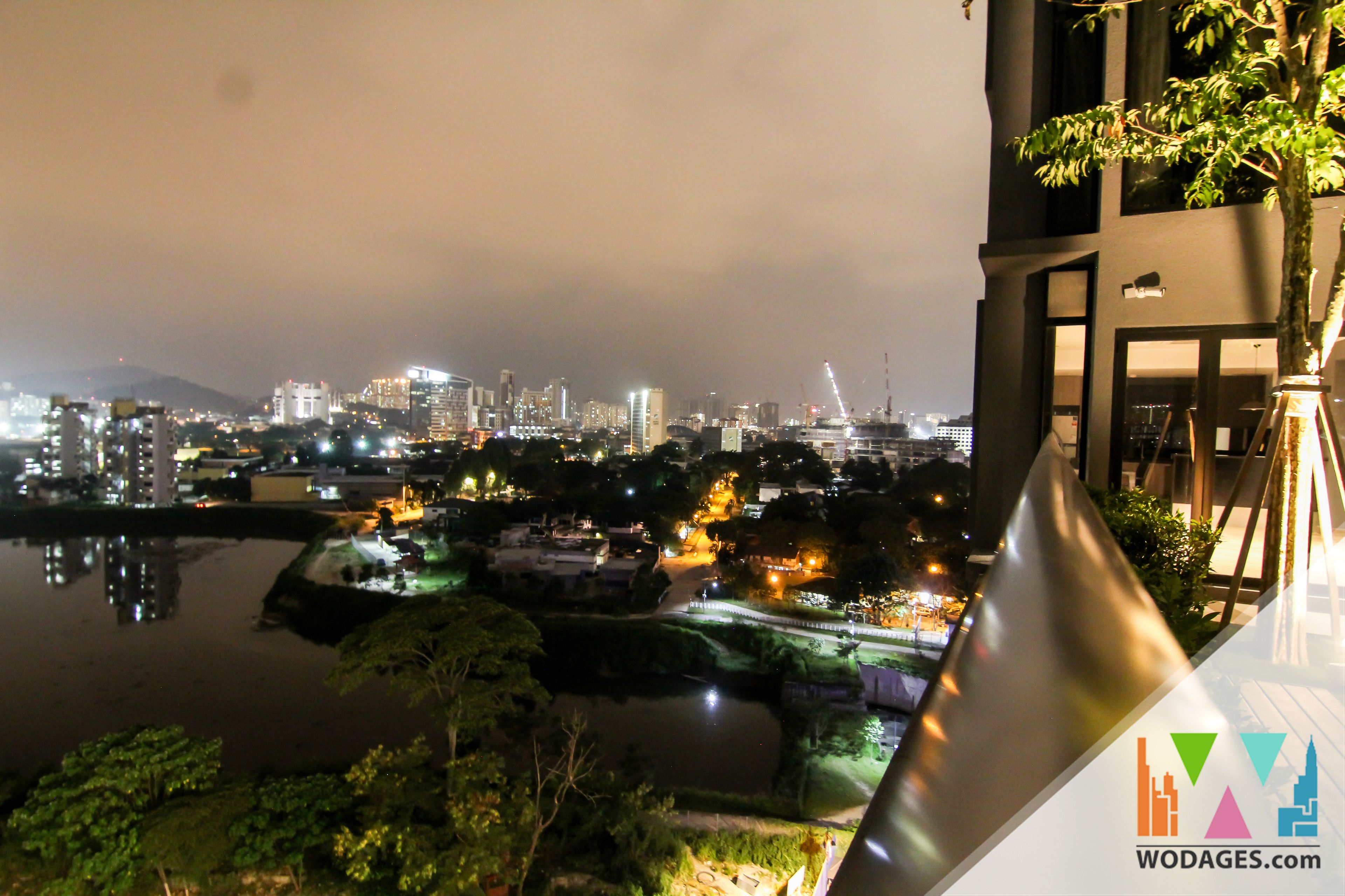A nighttime cityscape with illuminated buildings and a body of water.