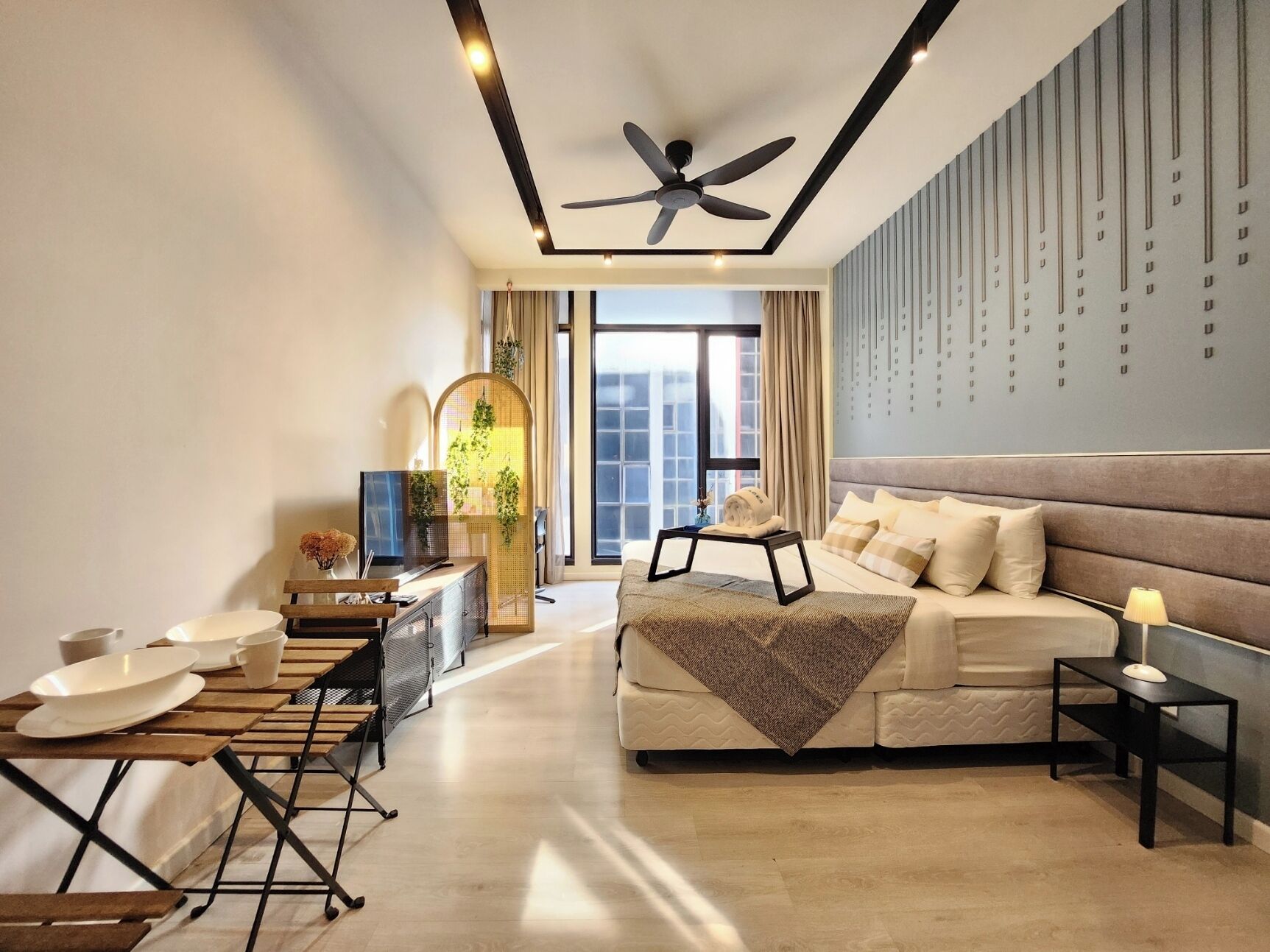 A modern hotel room with a bed, a desk, a chair, and a dining area.