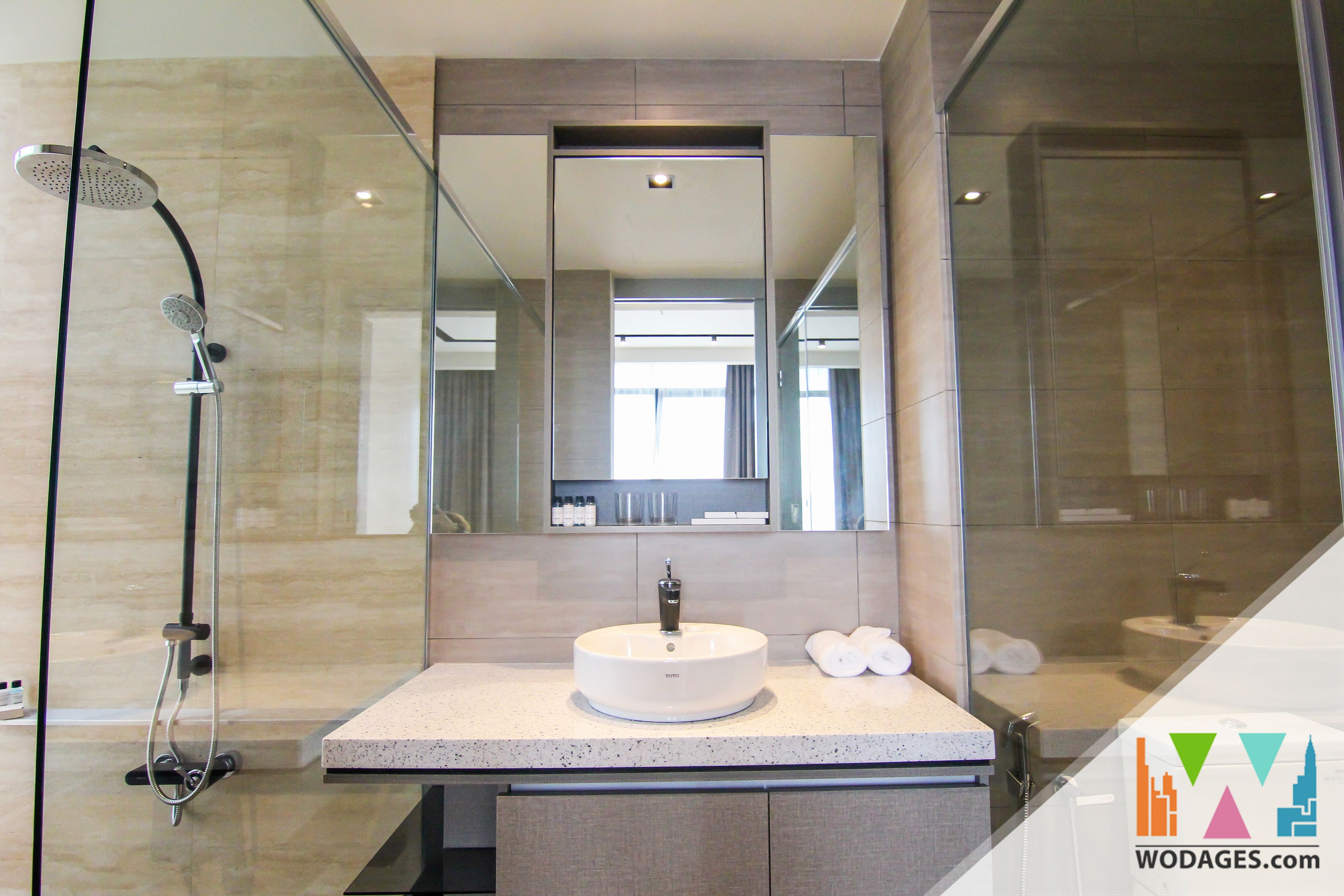 A modern bathroom with a glass-enclosed shower, a round sink, and a large mirror.
