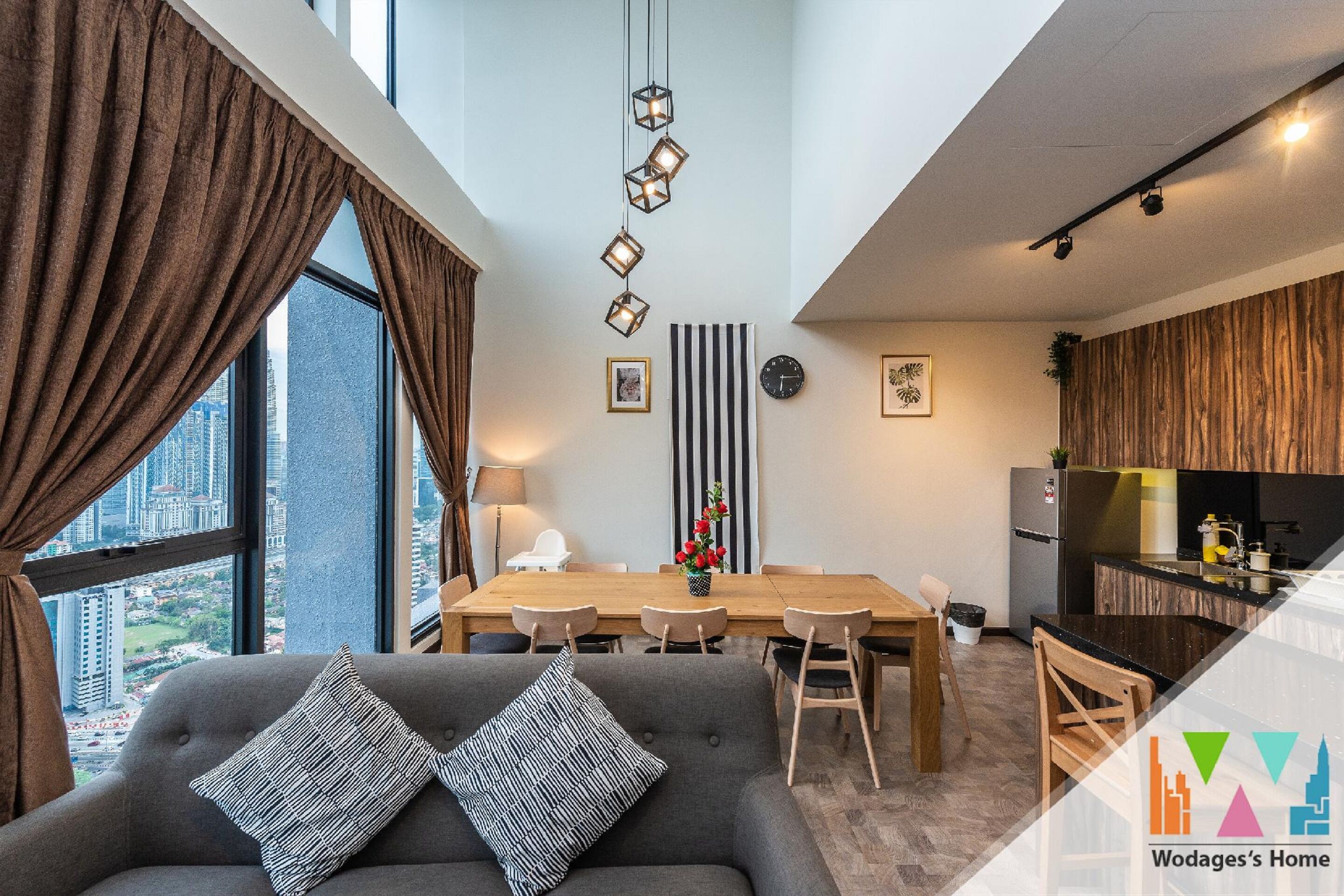 A modern living room with a sofa, dining table, and kitchen area.