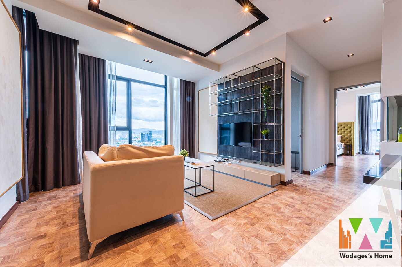 A modern living room with a sofa, a TV mounted on a wall, and a large window offering a city view.