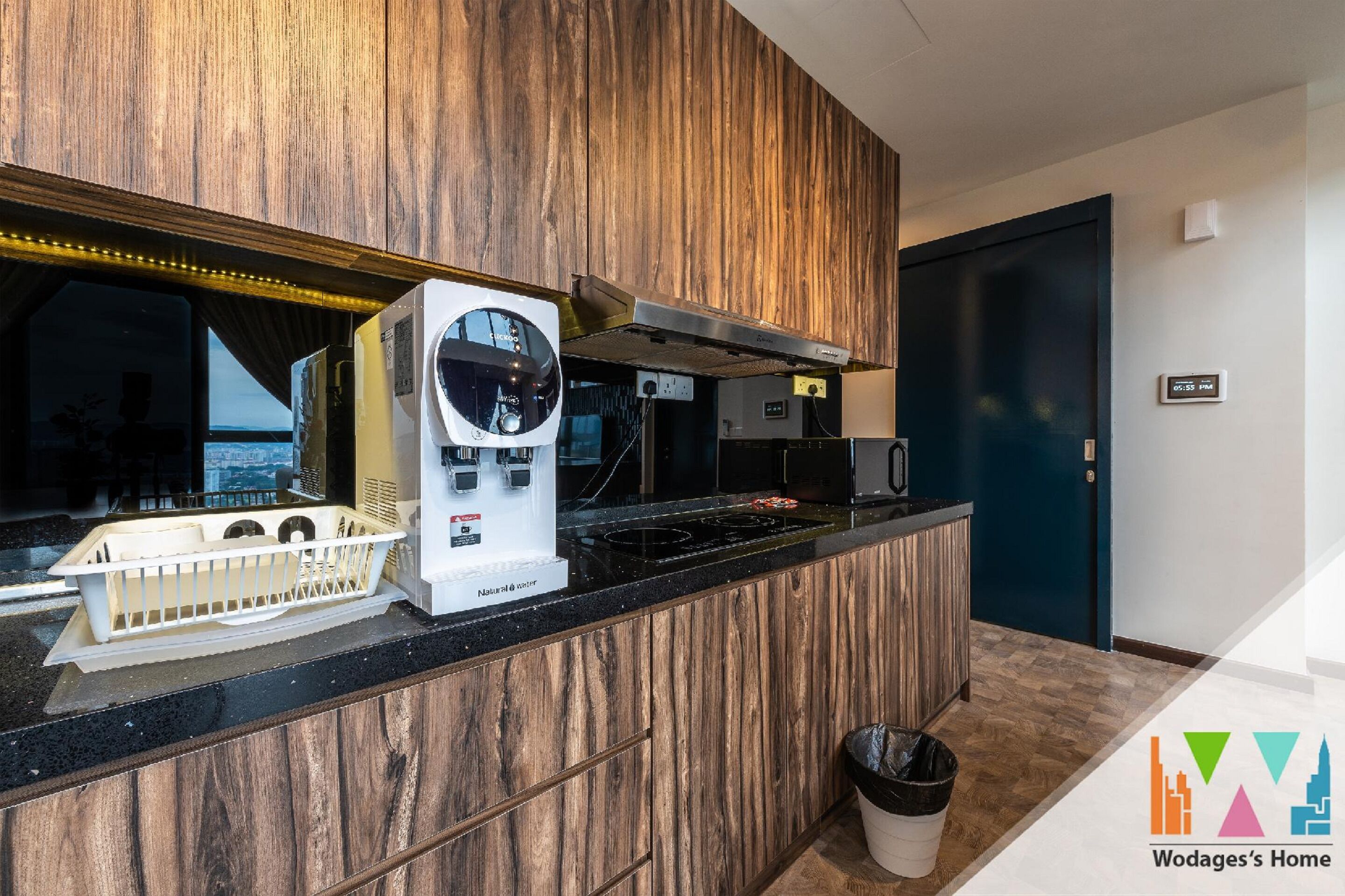 A kitchen with a built-in coffee machine, a stove, and a trash bin.