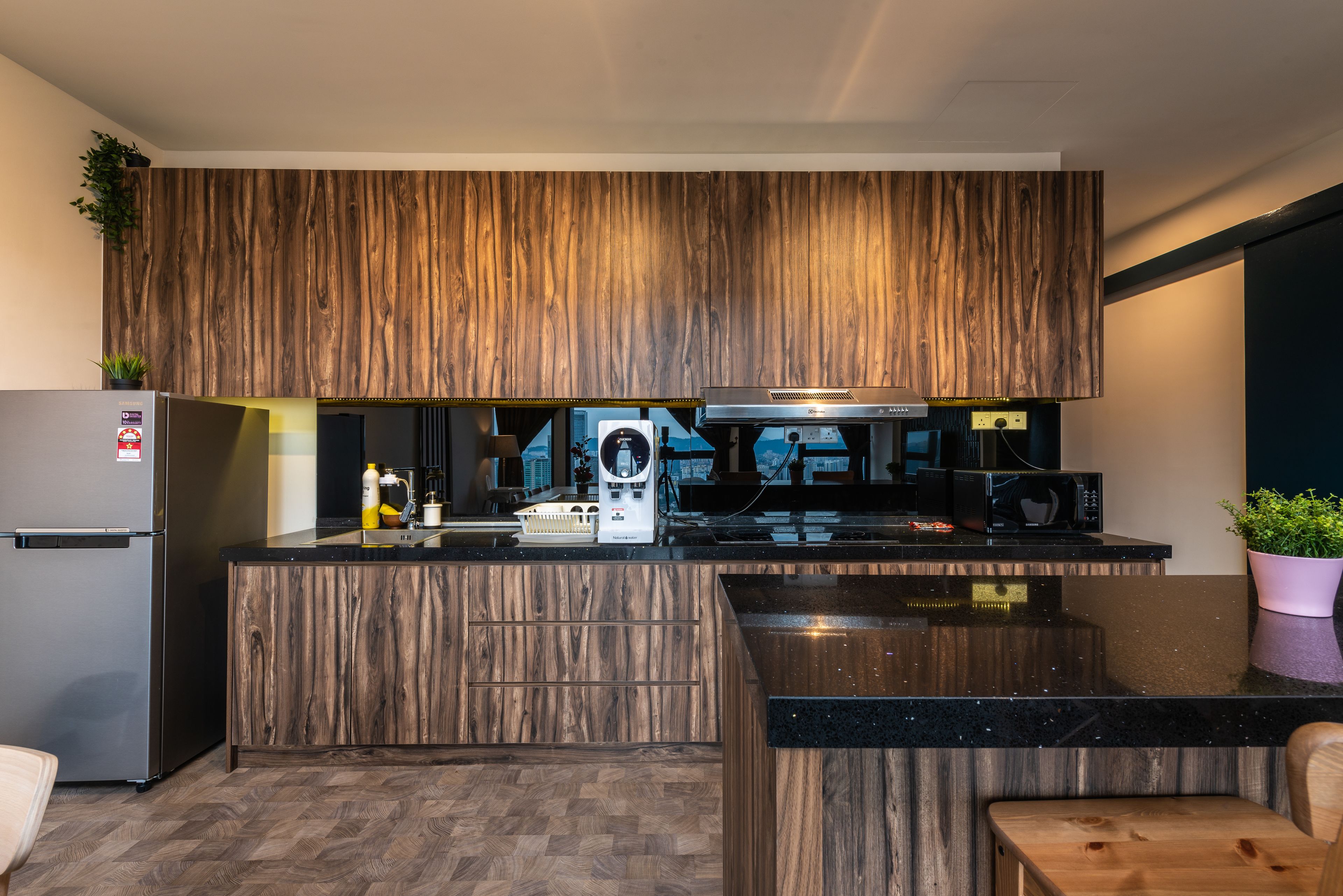 Een moderne keuken met houten kastjes, een ingebouwde magnetron en een roestvrijstalen koelkast.