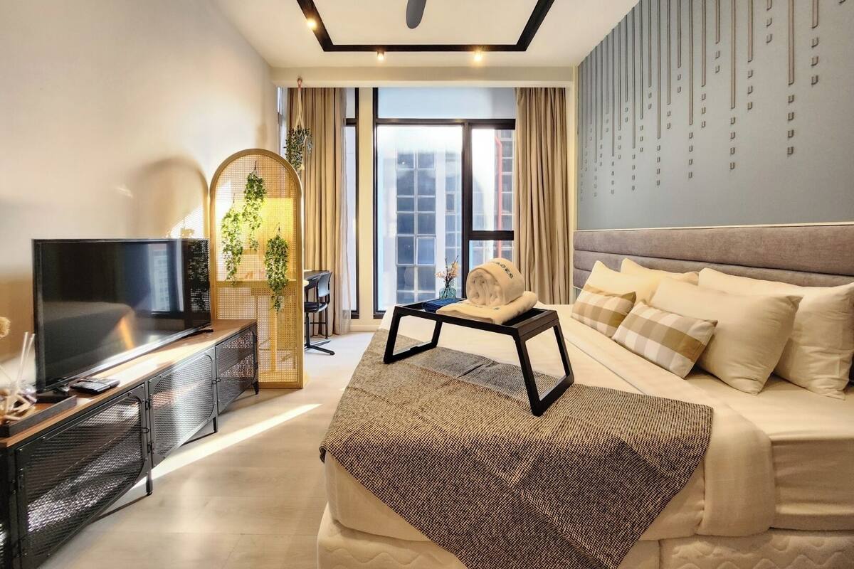 A modern hotel room with a bed, a television, a desk, and a large window.