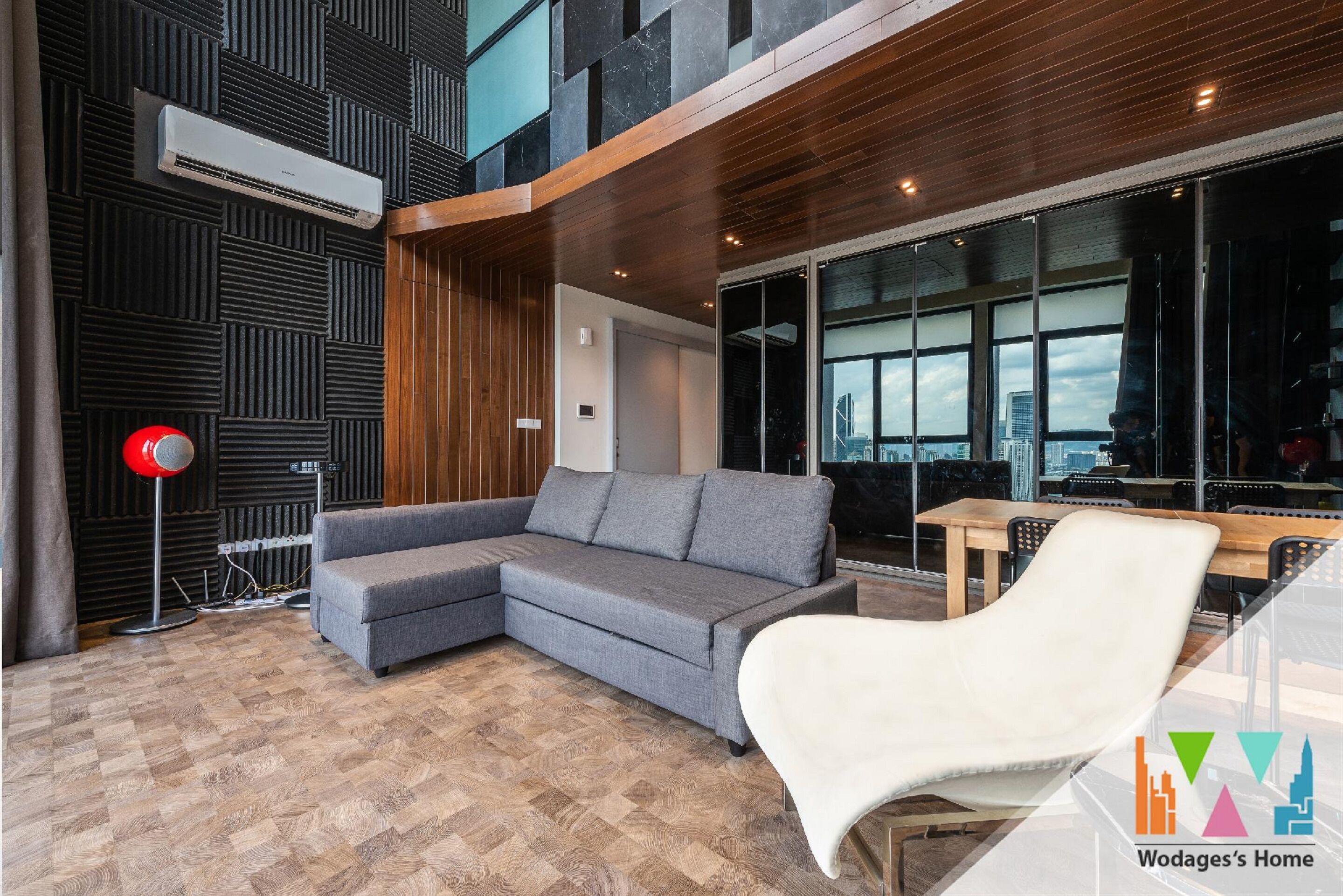 Un salón moderno con un sofá seccional gris, un sillón blanco y piso de madera.