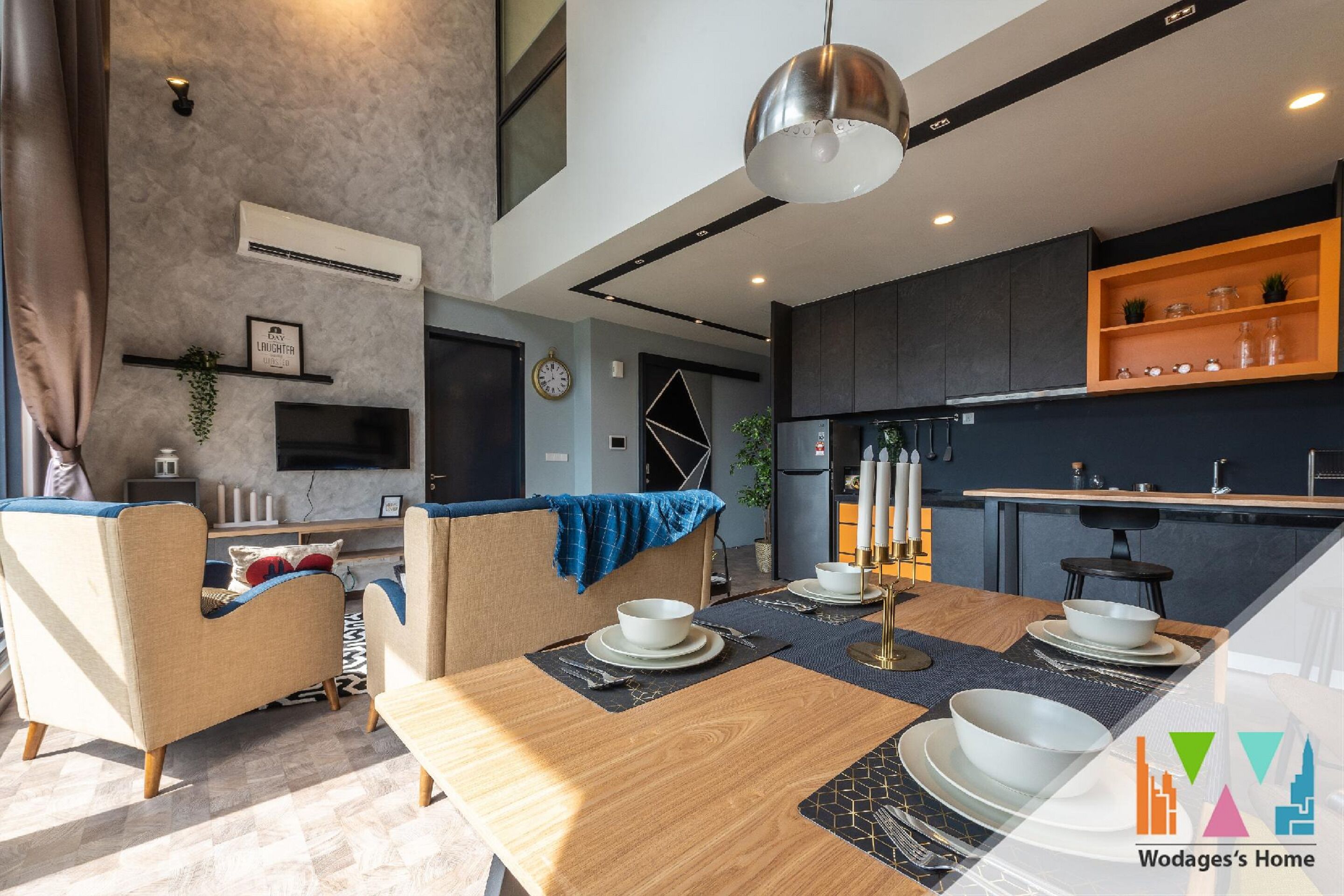 Une cuisine moderne avec un coin repas, comprenant une table en bois pour quatre personnes, un four encastré et un îlot central doté d’un évier.