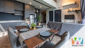 Eine moderne Küche mit dunklen Schränken, einem eingebauten Ofen und einem Essbereich mit einem Holztisch, gedeckt für vier Personen.