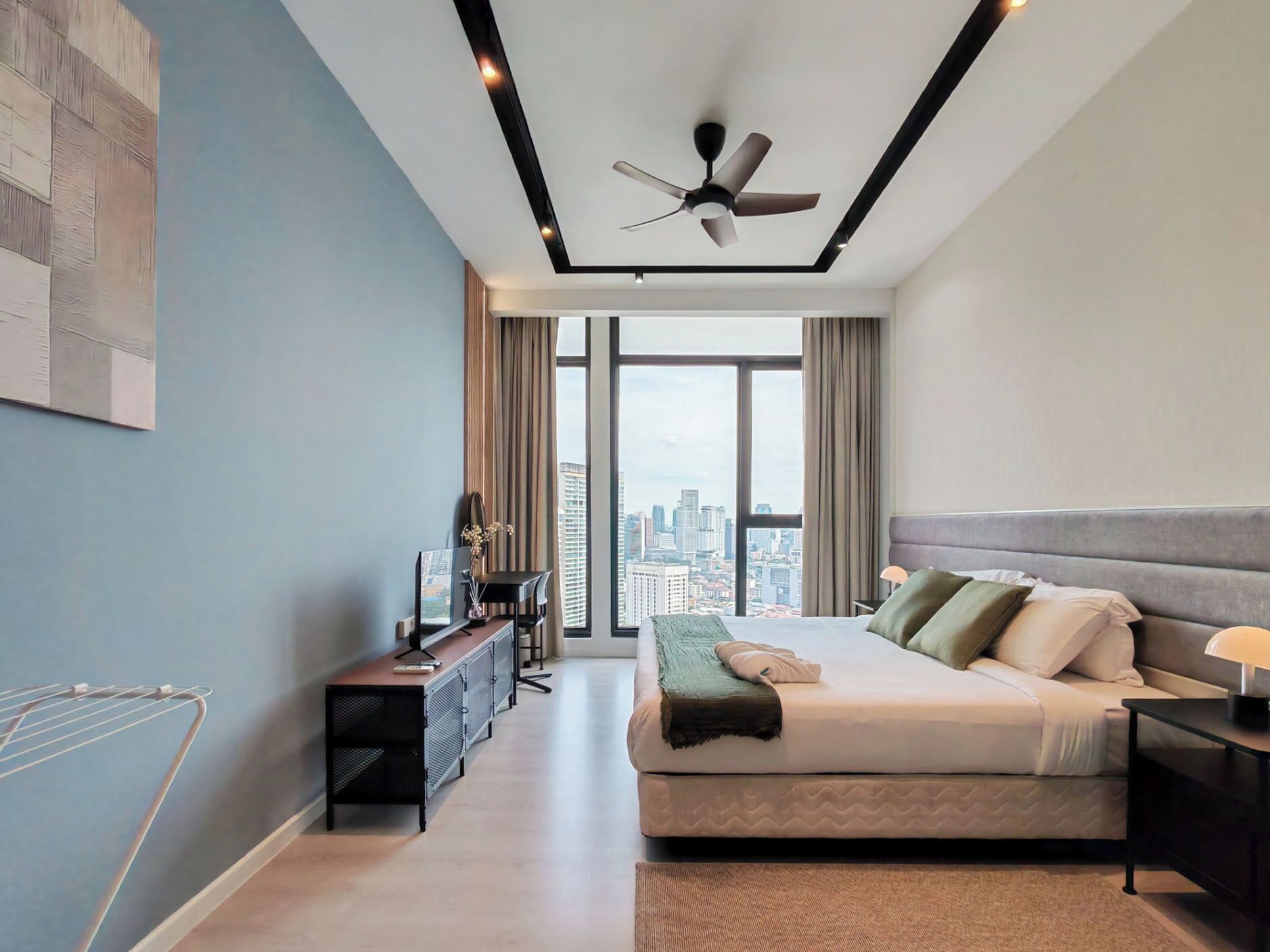 Une chambre moderne avec un lit, un bureau et une grande fenêtre donnant sur la ville.