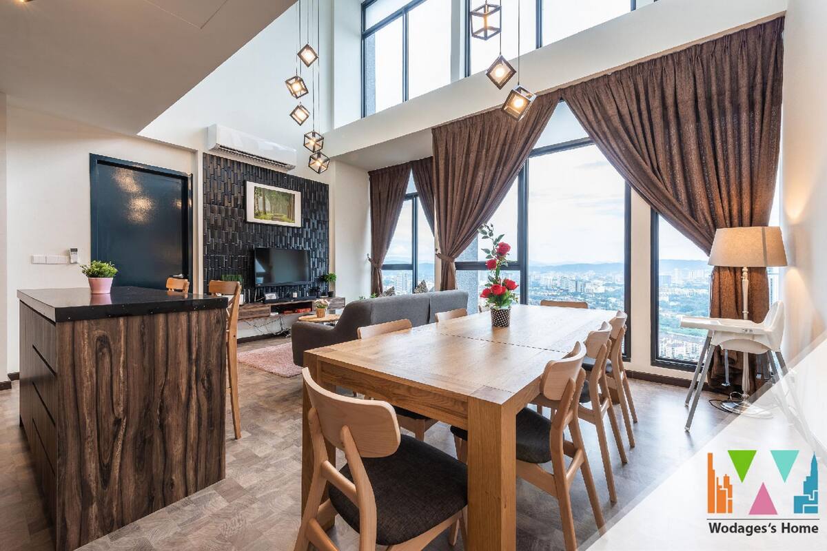 A modern living room with a wooden dining table, sofa, and a TV mounted on the wall.