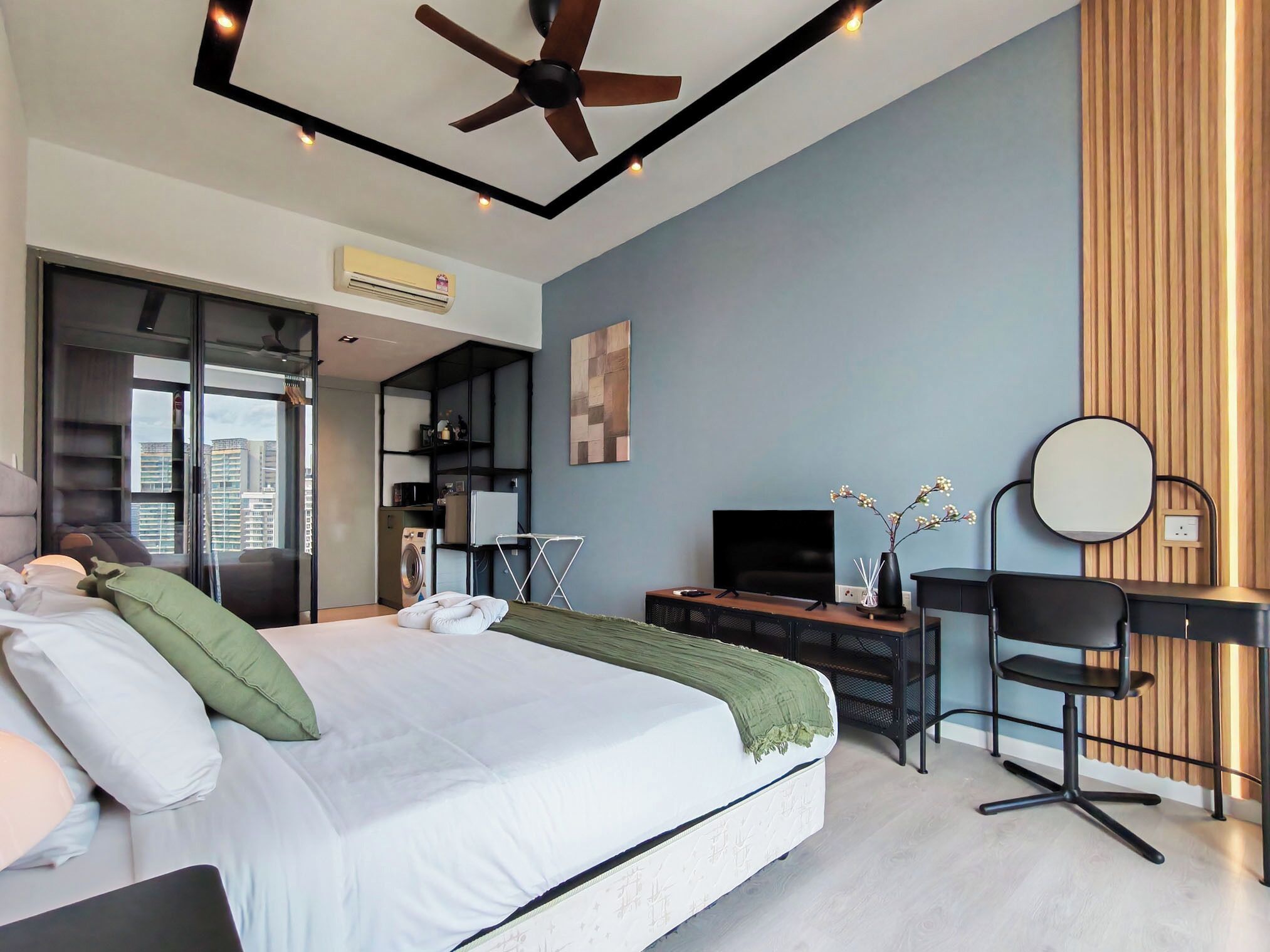A modern bedroom with a bed, a desk, a chair, a TV, and a ceiling fan.