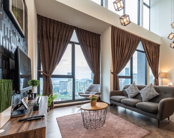 A modern living room with a large window, a sofa, a coffee table, and a TV.