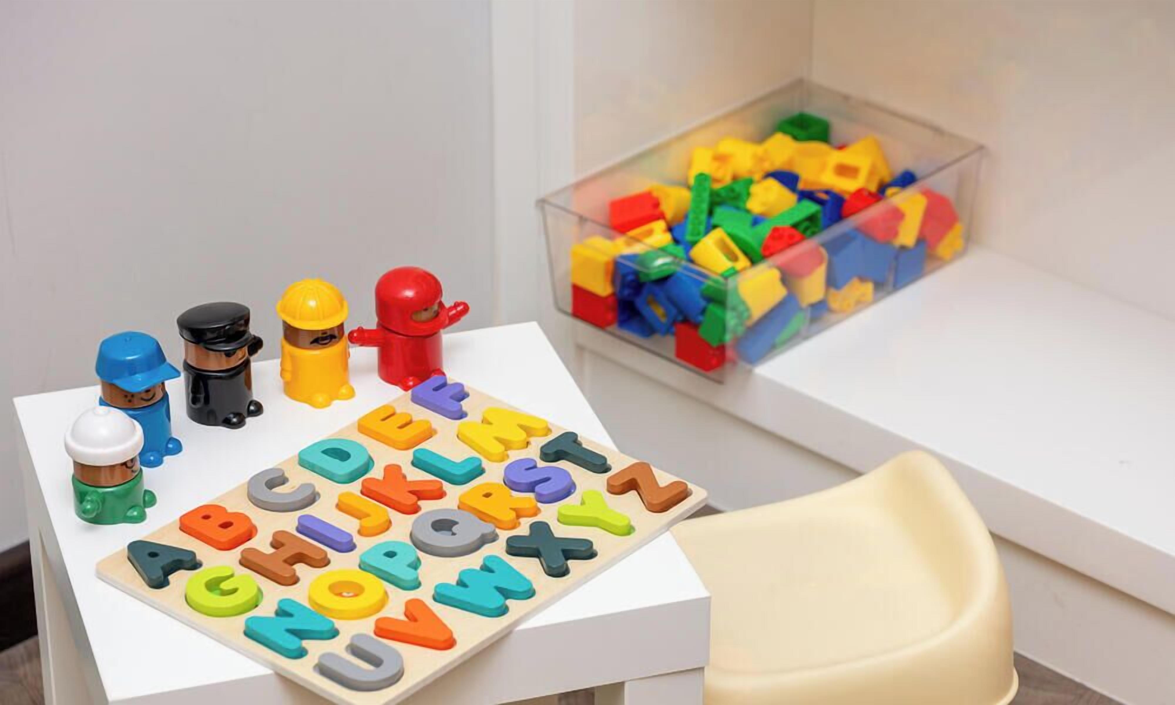 A play area with alphabet blocks, toy figures, and a storage box of colorful building blocks.