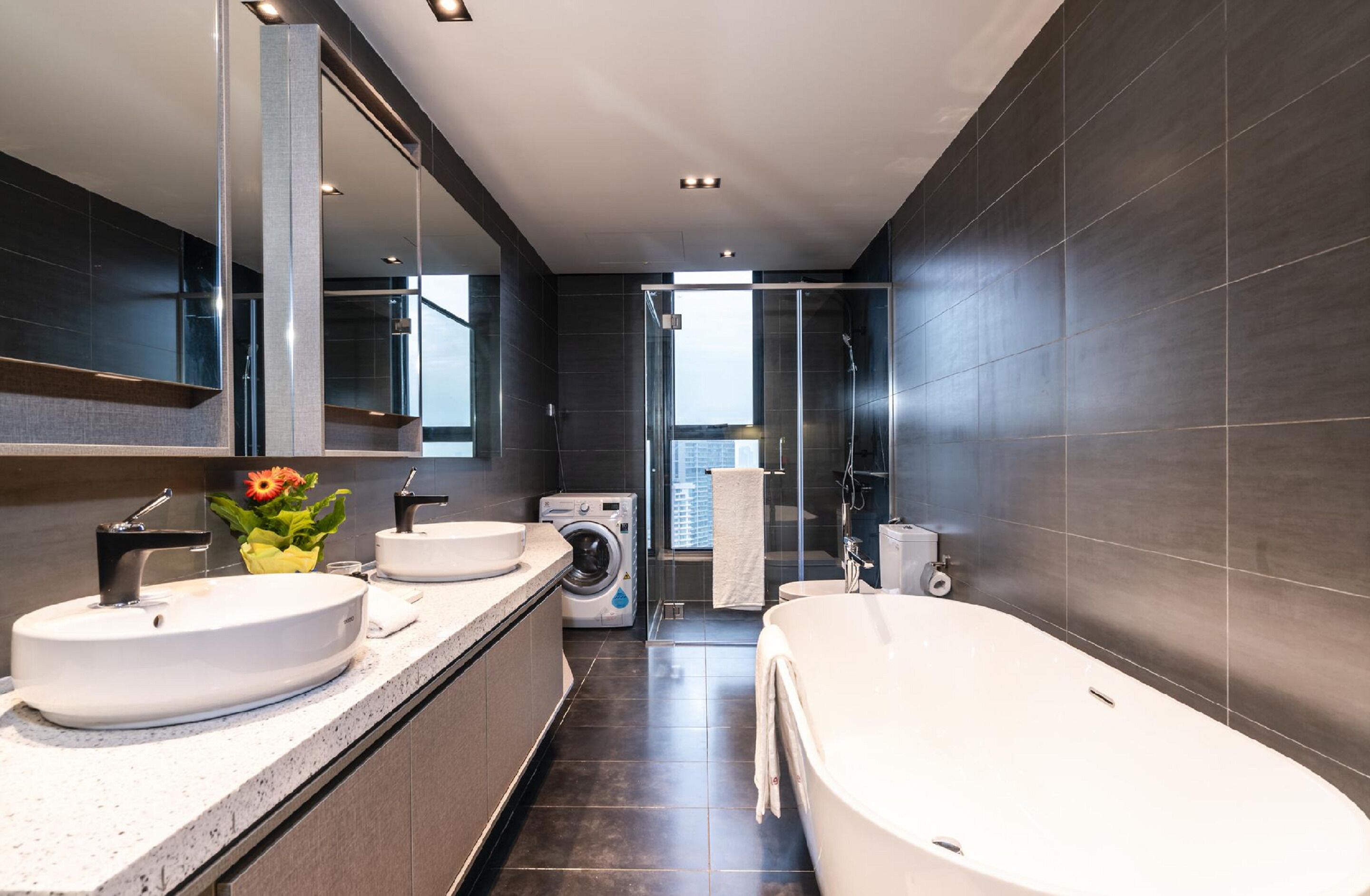 A modern bathroom with a large mirror, two sinks, a bathtub, and a shower.