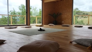 A spacious room with wooden flooring, large windows, and a view of greenery outside. - Biovilla Sustentabilidade (Palmela)