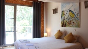 A bedroom with a bed, pillows, a painting, and a window with curtains. - Biovilla Sustentabilidade (Palmela)