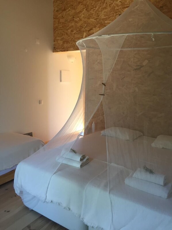 Una habitación con una cama bajo un dosel, otra cama y una pared de madera.