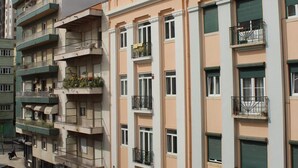 A multi-story residential building with balconies, a parking area in front, and a clear sky. - TripGeo Apartment Roma (Lisbon)