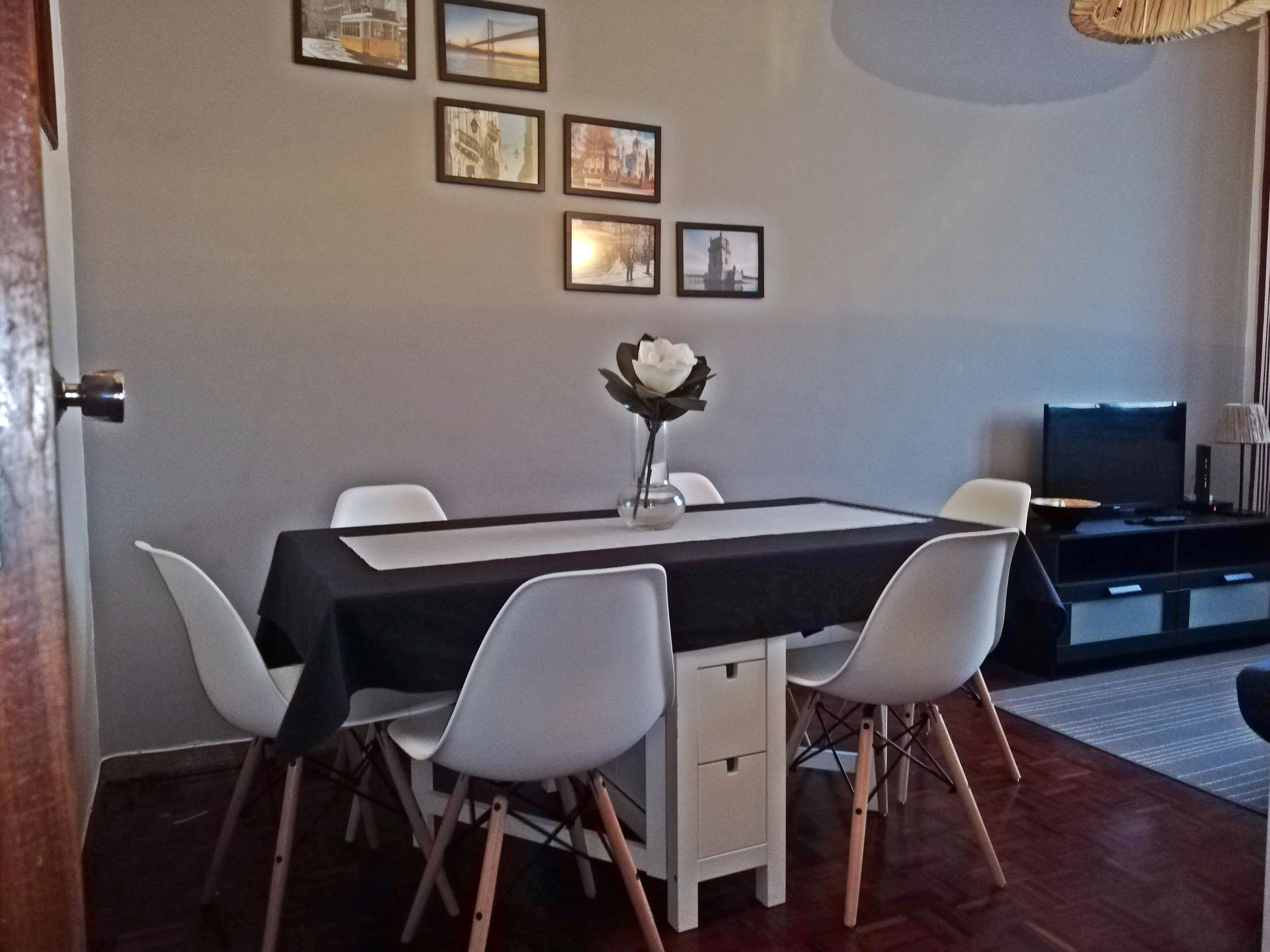 A dining area with a table, chairs, and a vase with flowers.