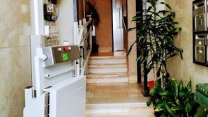 A hallway with a white appliance, a staircase, and potted plants. - TripGeo Apartment Roma (Lisbon)