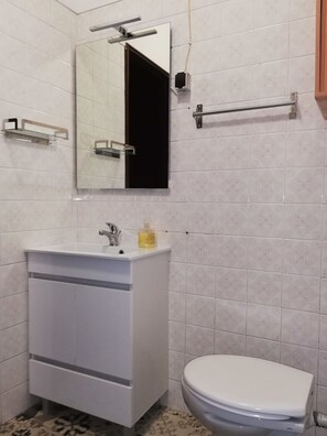 A bathroom with a white sink, mirror, and toilet. There are two towel bars and a soap dispenser on the sink. - TripGeo Apartment Roma (Lisbon)